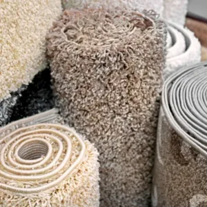 Différents types de tapis et moquettes présentés sur un sol, illustrant une variété de textures et de motifs.