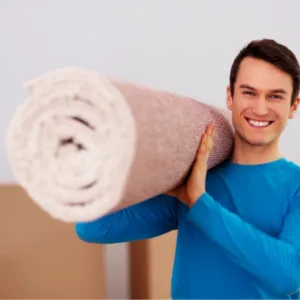 Un homme tenant un grand rouleau de tapis.