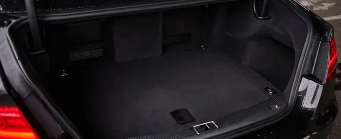 Open trunk of a black car showing a clean, spacious cargo area with a protective mat.