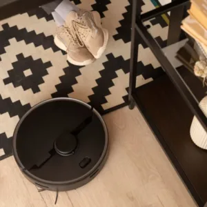 Une personne assise par terre à côté d'un aspirateur robot.