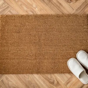 Un paillasson marron avec des chaussures blanches posées dessus.