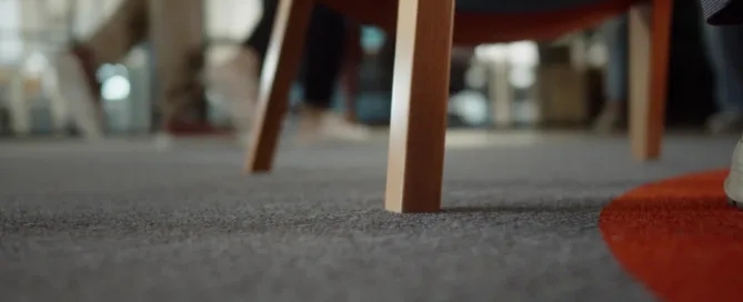 A person sitting on a chair in a room with a floor mat beneath them.