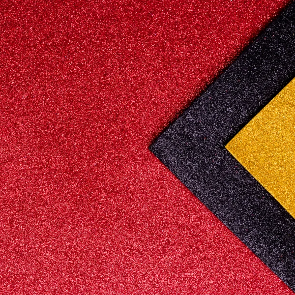 Un carré rouge, jaune et noir sur un fond rouge, représentant un tapis mural moderne.
